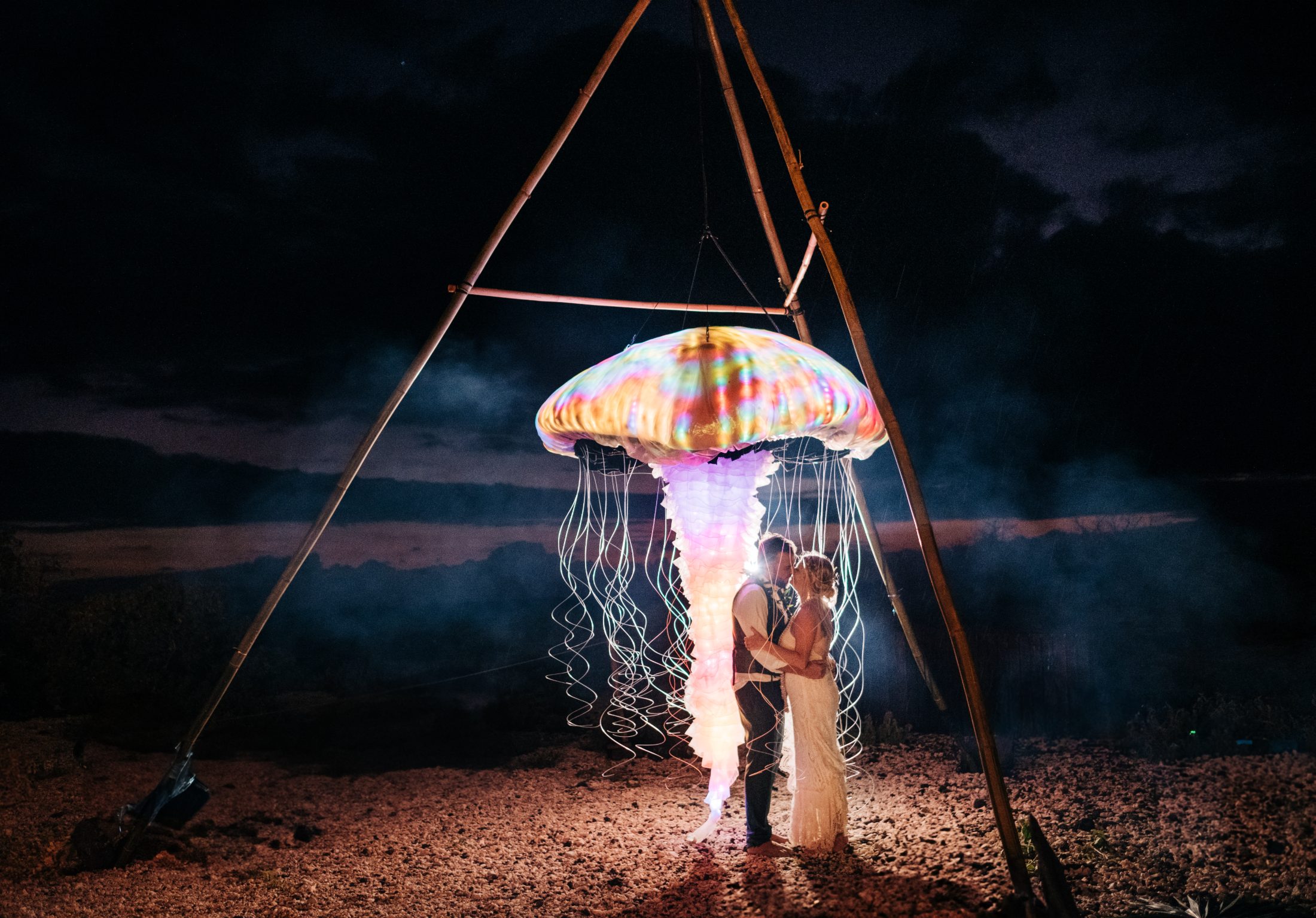 Bride and groom beneath a glowing LED jellyfish sculpture at their Big Island wedding reception