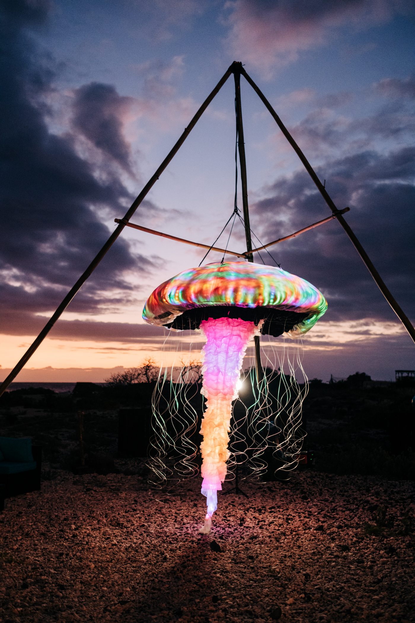 LED jellyfish sculpture suspended from a bamboo tripod against a Kona sunset at a Big Island wedding
